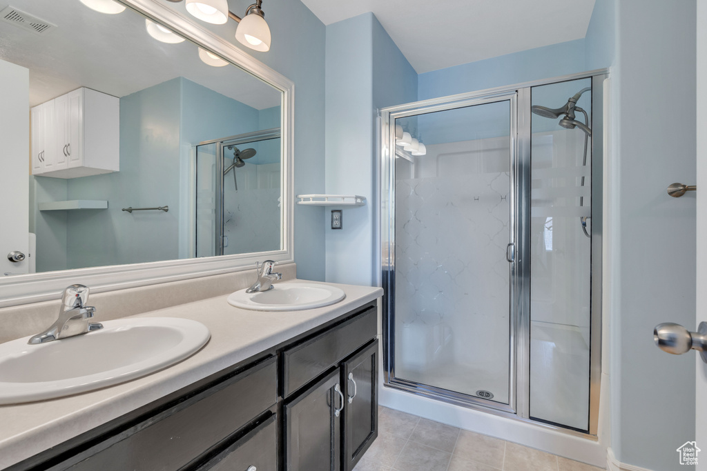 Bathroom with double sink, tile floors, oversized vanity, and walk in shower
