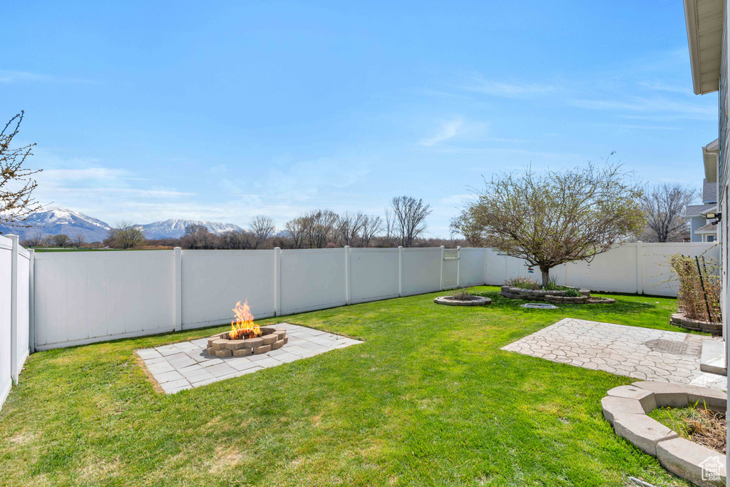View of yard featuring a fire pit, a mountain view, and a patio