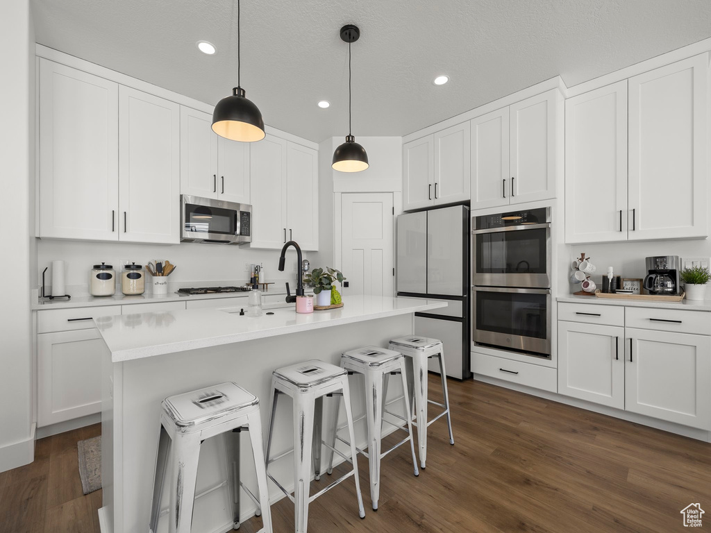 Kitchen featuring white cabinets, dark wood-type flooring, and appliances with stainless steel finishes