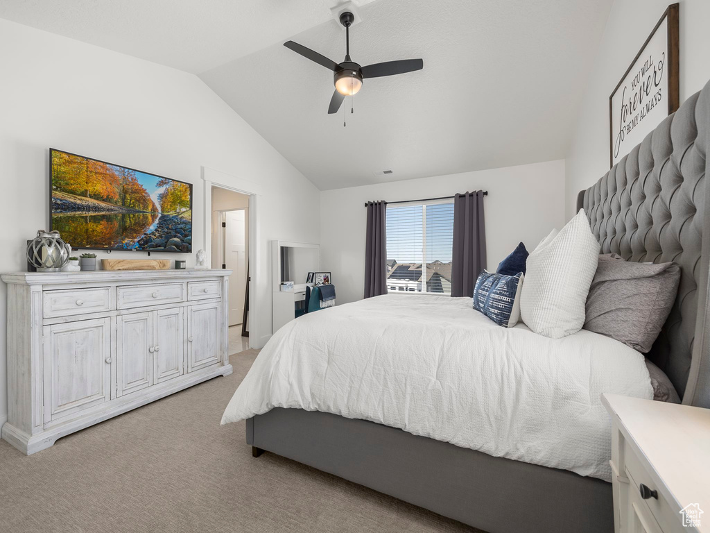 Carpeted bedroom with connected bathroom, ceiling fan, and lofted ceiling