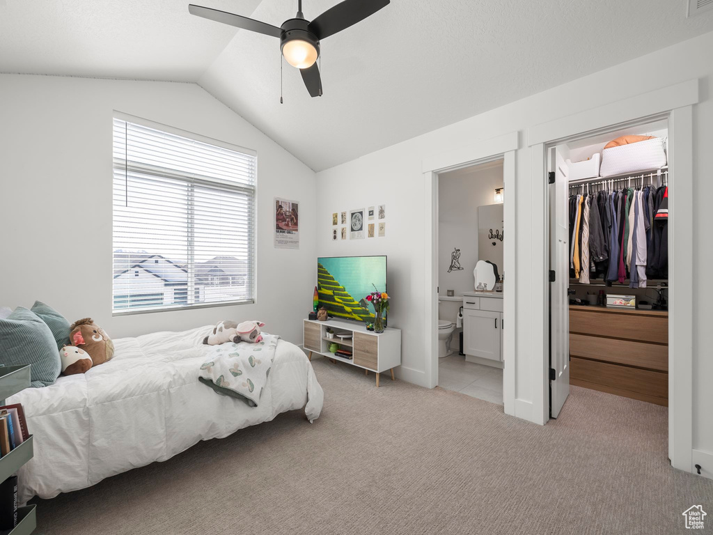 Bedroom featuring ceiling fan, a closet, vaulted ceiling, ensuite bath, and light carpet