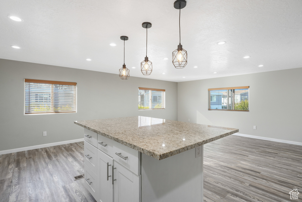 Kitchen featuring decorative light fixtures, white cabinetry, a center island, and light hardwood / wood-style floors