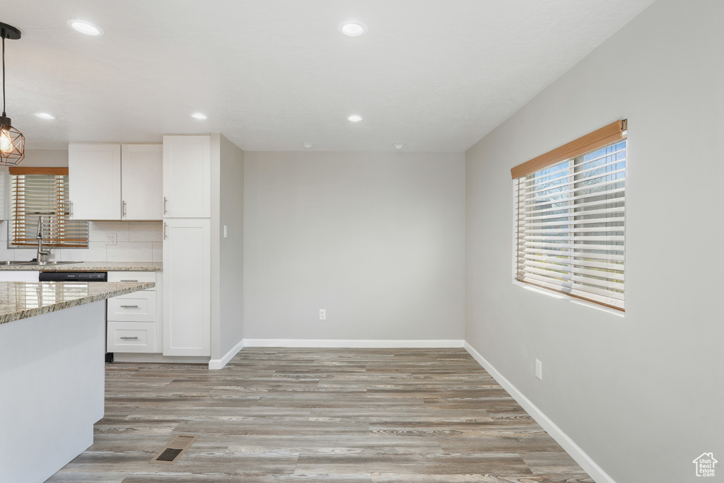 Kitchen with white cabinets, backsplash, light hardwood / wood-style flooring, and pendant lighting