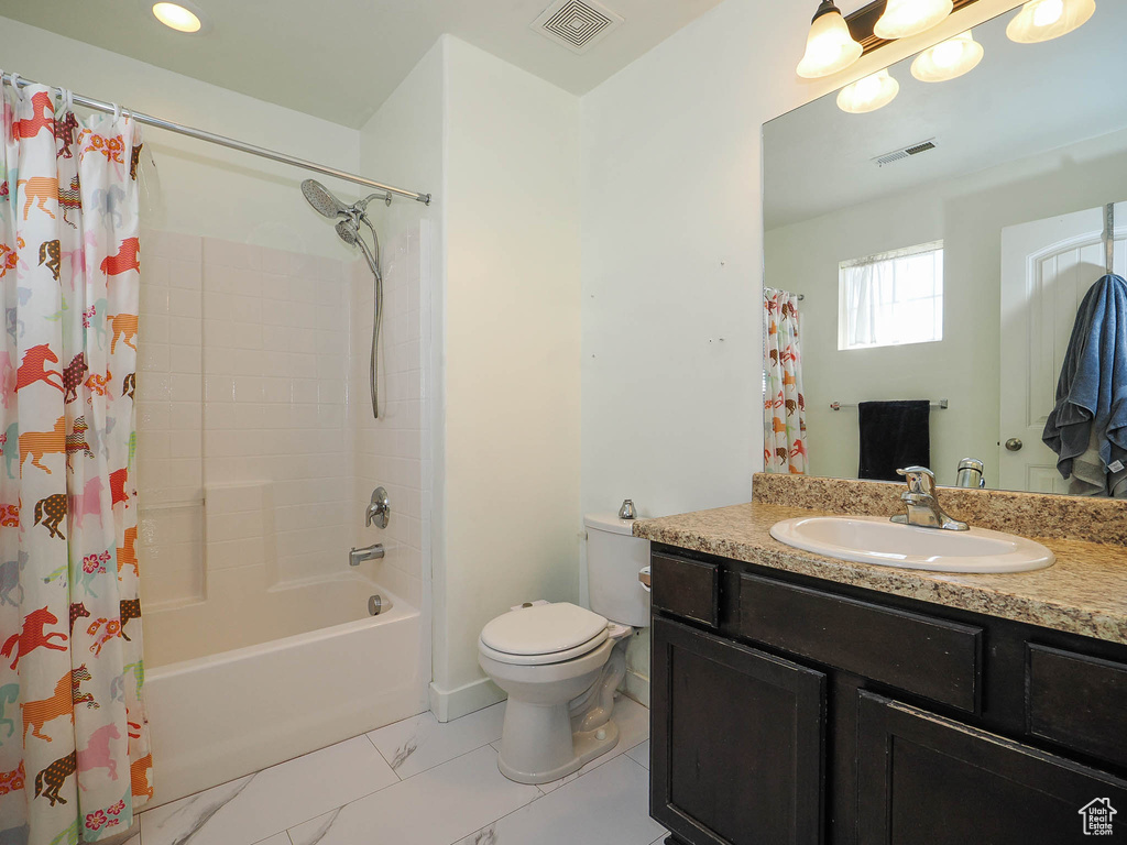 Full bathroom featuring tile flooring, toilet, vanity, and shower / bath combo with shower curtain
