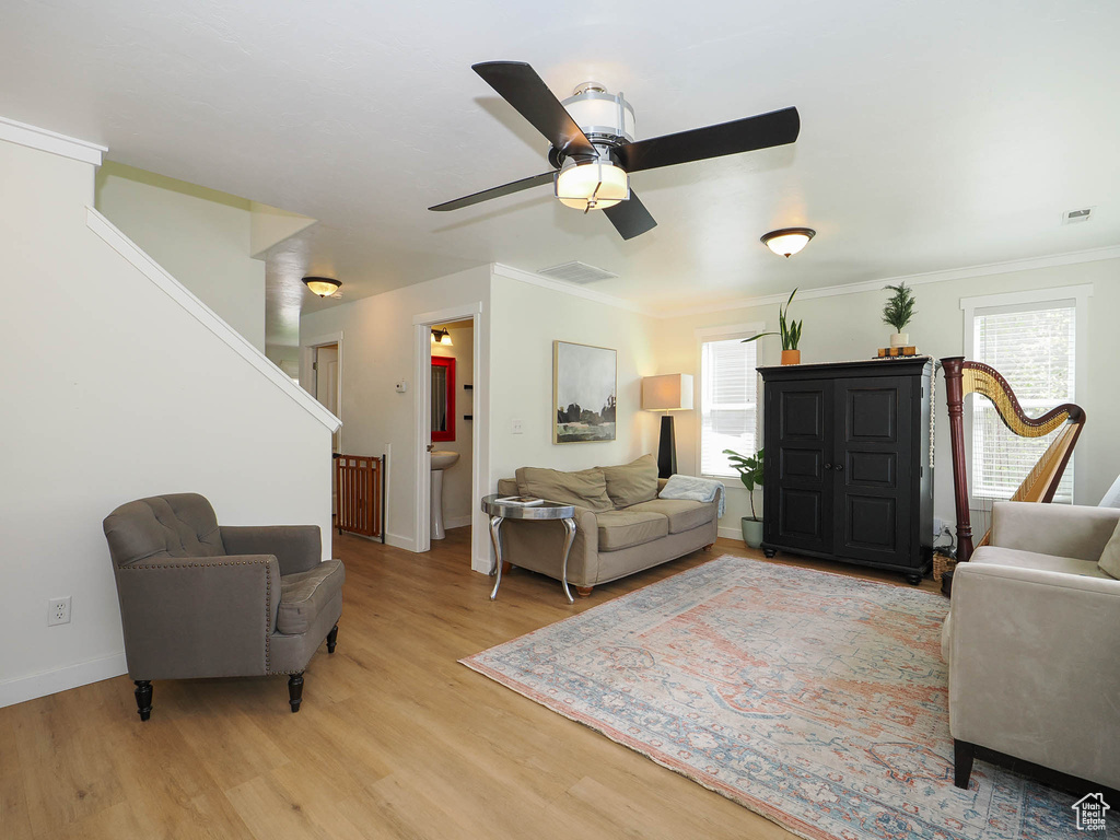 Living room with ceiling fan, crown molding, light hardwood / wood-style floors, and a healthy amount of sunlight