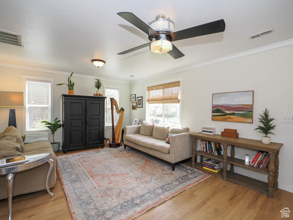Living room featuring light hardwood / wood-style flooring, ceiling fan, and crown molding