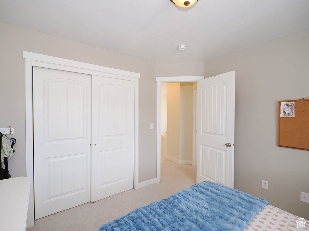 Bedroom with light colored carpet and a closet