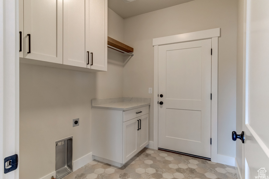Laundry room with electric dryer hookup, cabinets, and light tile floors