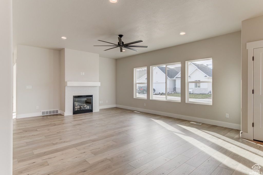 Unfurnished living room featuring ceiling fan, light hardwood / wood-style flooring, and a healthy amount of sunlight