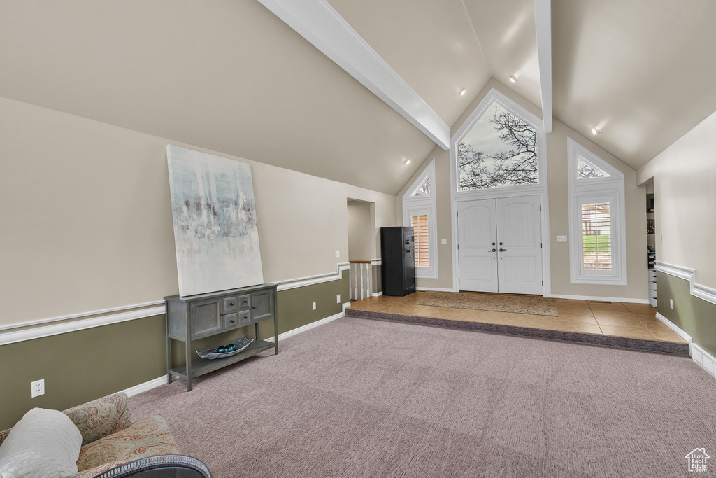 Foyer with lofted ceiling with beams and light carpet