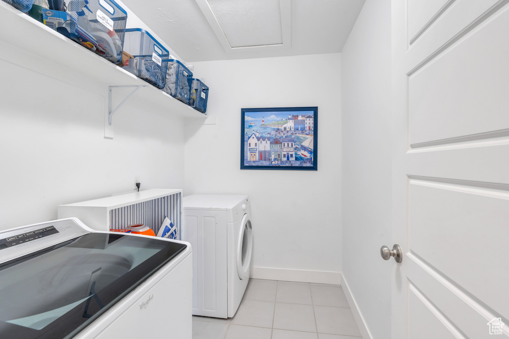 Clothes washing area featuring separate washer and dryer and light tile floors