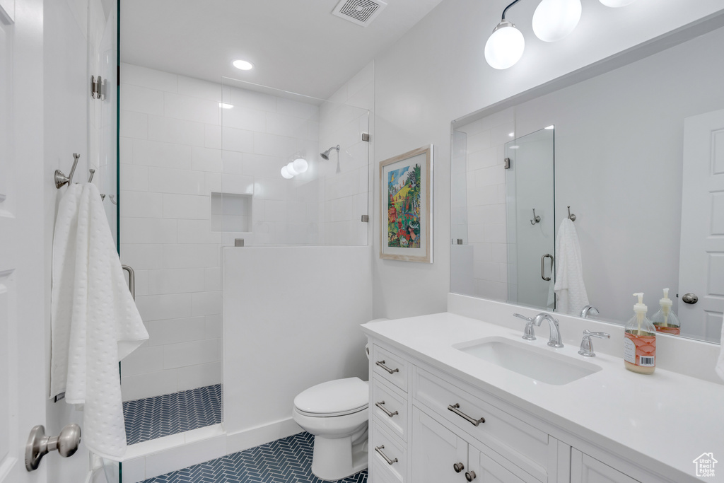 Bathroom with toilet, tile floors, tiled shower, and vanity