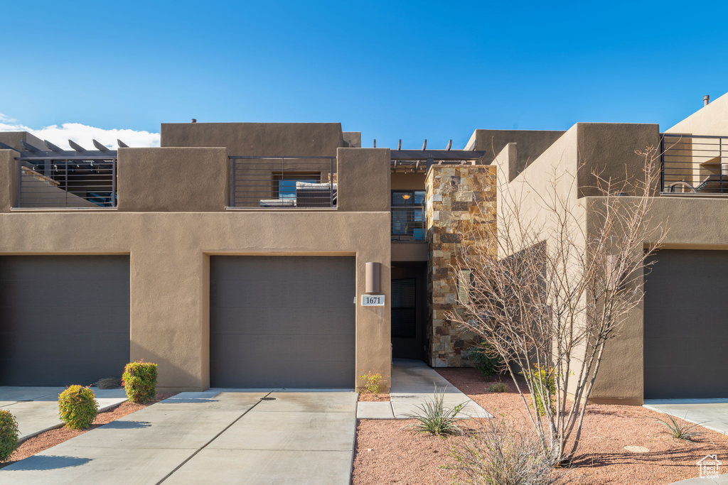 Pueblo revival-style home featuring a balcony and a garage