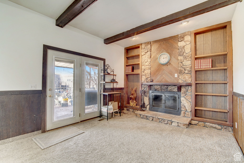 Carpeted living room featuring a fireplace and beamed ceiling