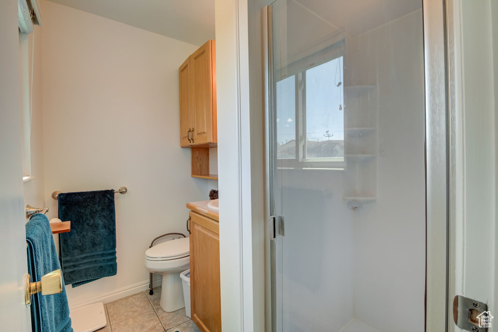 Bathroom with tile flooring, a shower with door, vanity, and toilet