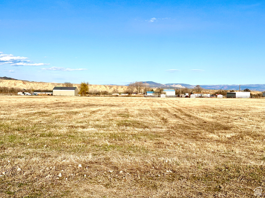 View of yard featuring a rural view, an outdoor structure, and a mountain view