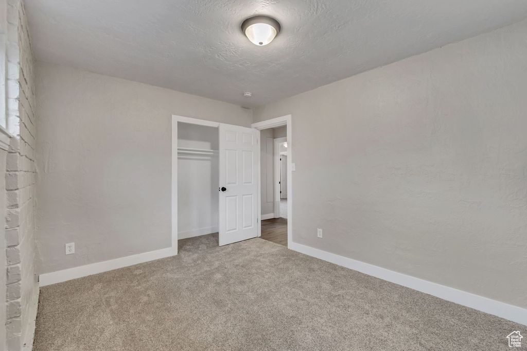 Unfurnished bedroom featuring dark carpet and a closet