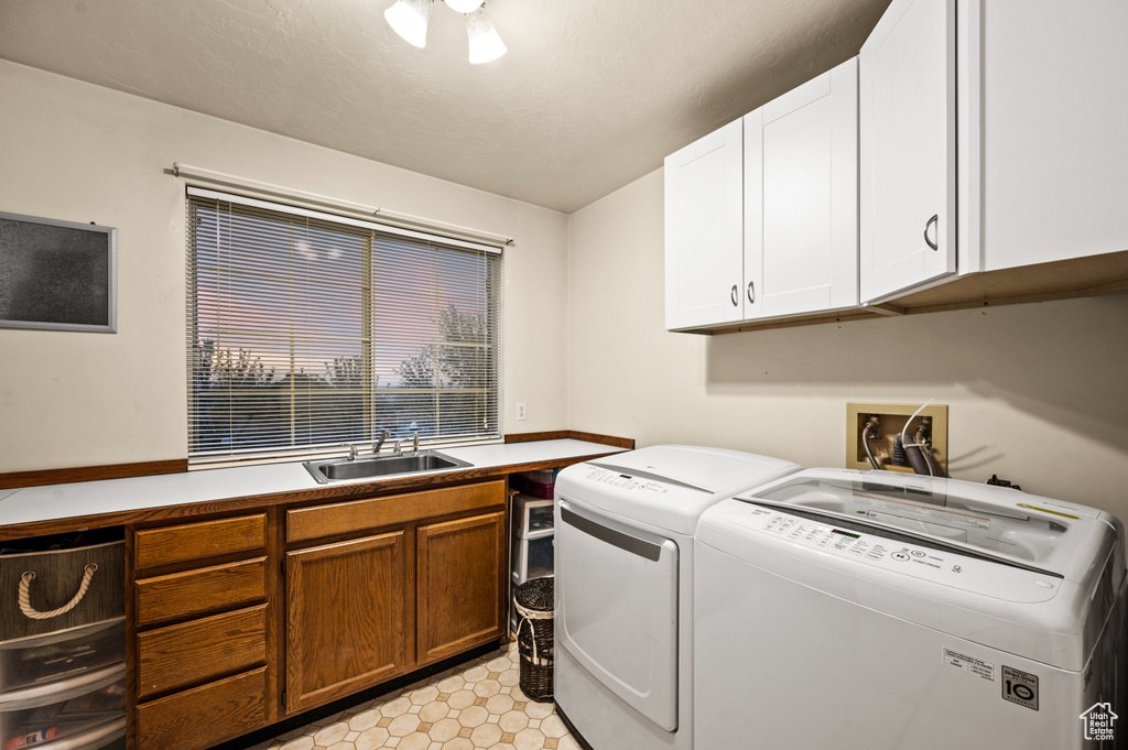 Laundry room with light tile floors, hookup for a washing machine, sink, washing machine and clothes dryer, and cabinets