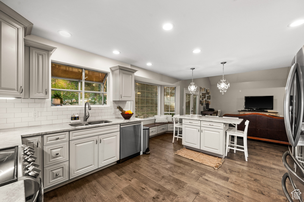 Kitchen featuring stainless steel appliances, backsplash, a notable chandelier, sink, and dark hardwood / wood-style floors
