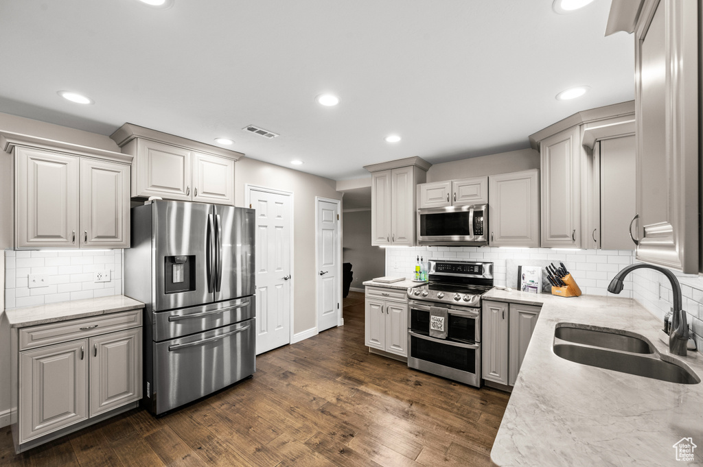 Kitchen featuring stainless steel appliances, dark wood-type flooring, and backsplash