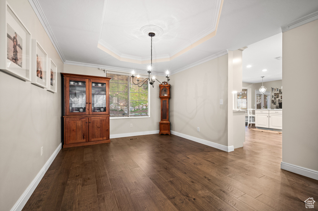 Interior space with an inviting chandelier, crown molding, a tray ceiling, and hardwood / wood-style floors