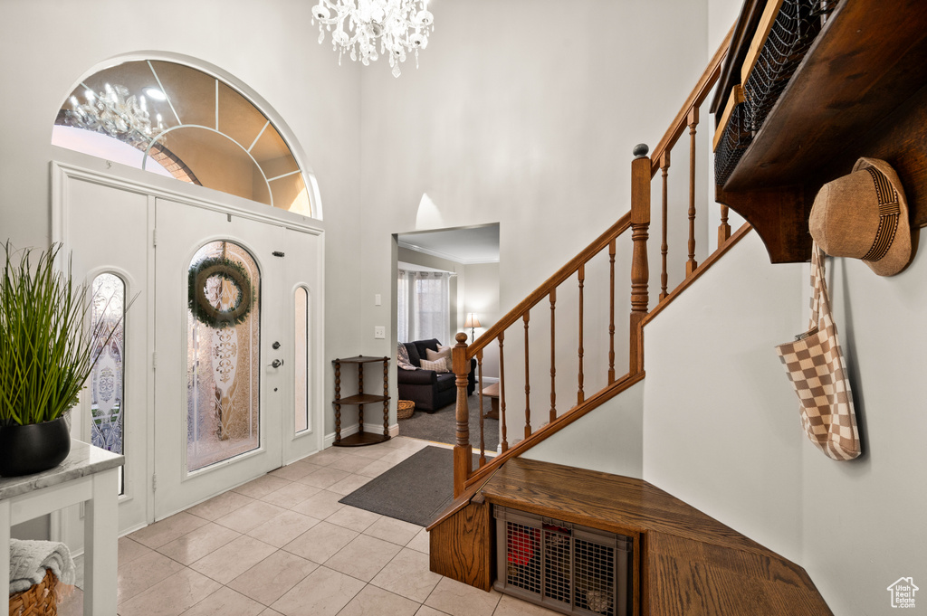 Tiled entrance foyer with a wealth of natural light, a high ceiling, and a chandelier