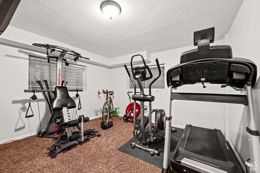 Exercise room featuring carpet and a textured ceiling