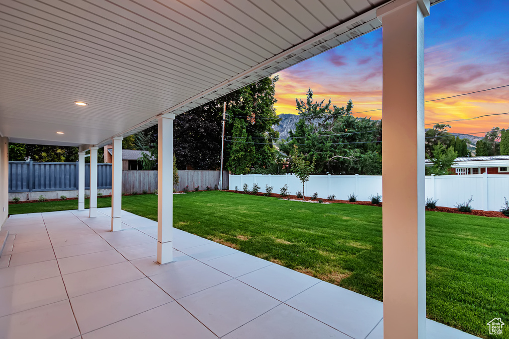 Patio terrace at dusk featuring a lawn