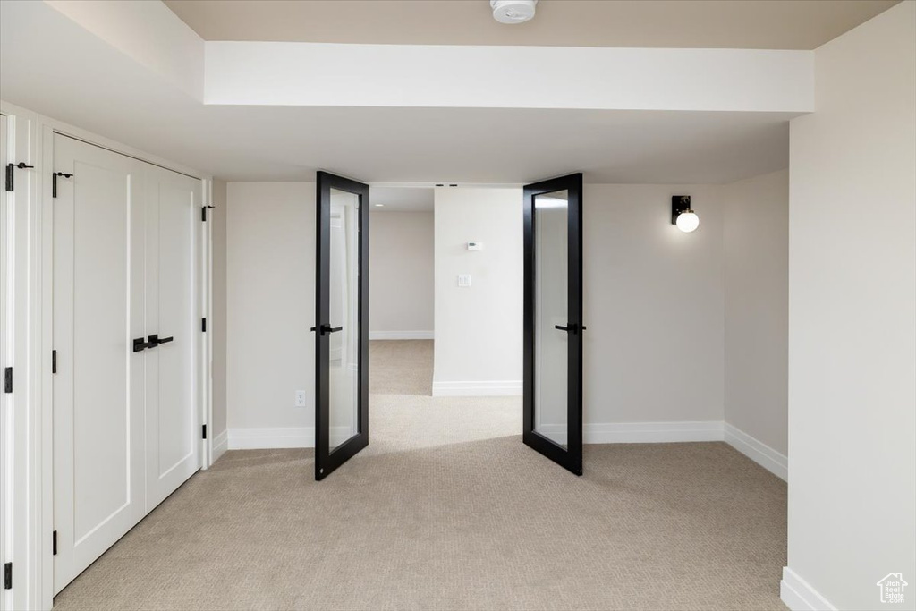 Basement with light colored carpet and french doors