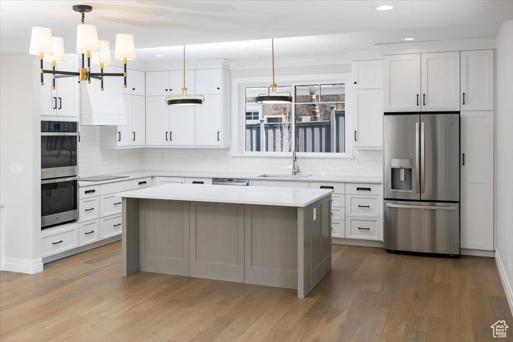 Kitchen with white cabinetry, appliances with stainless steel finishes, and light hardwood / wood-style floors