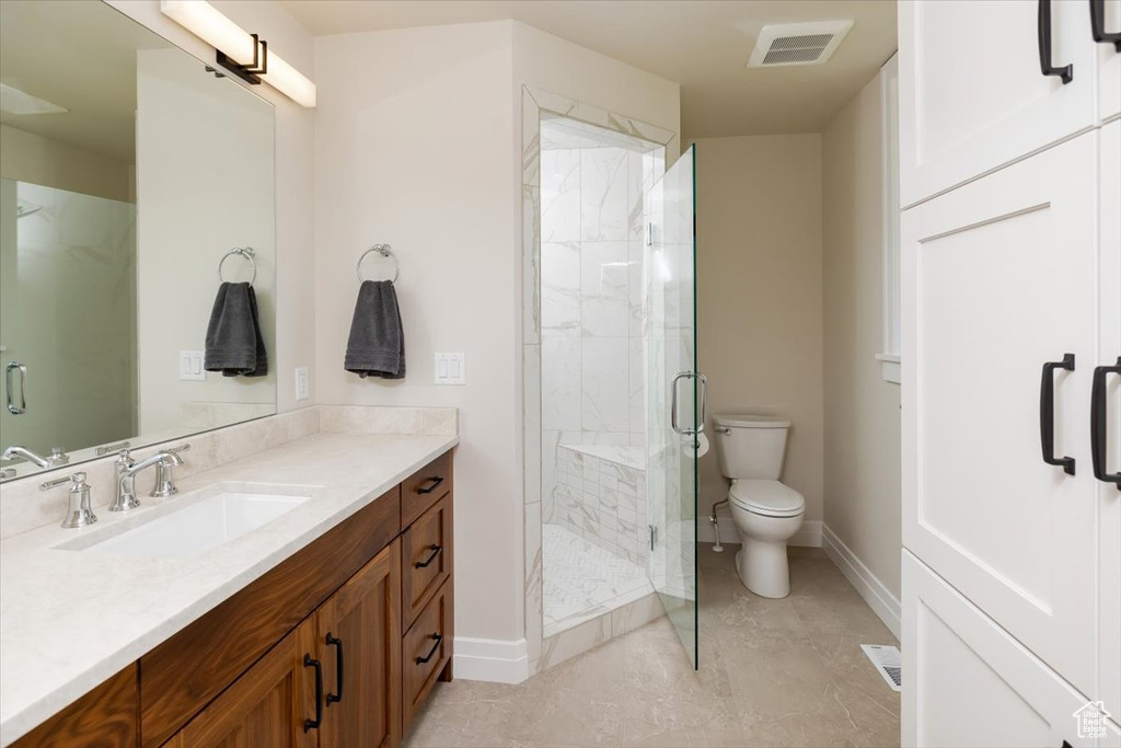 Bathroom featuring vanity, toilet, tile floors, and an enclosed shower