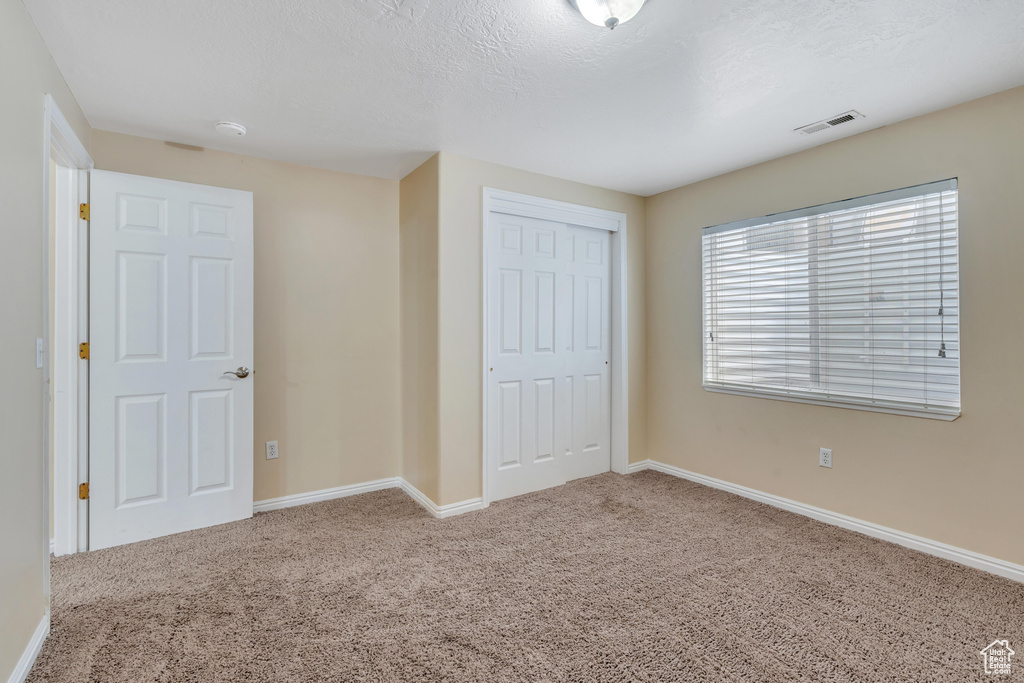 Unfurnished bedroom featuring a closet and light carpet