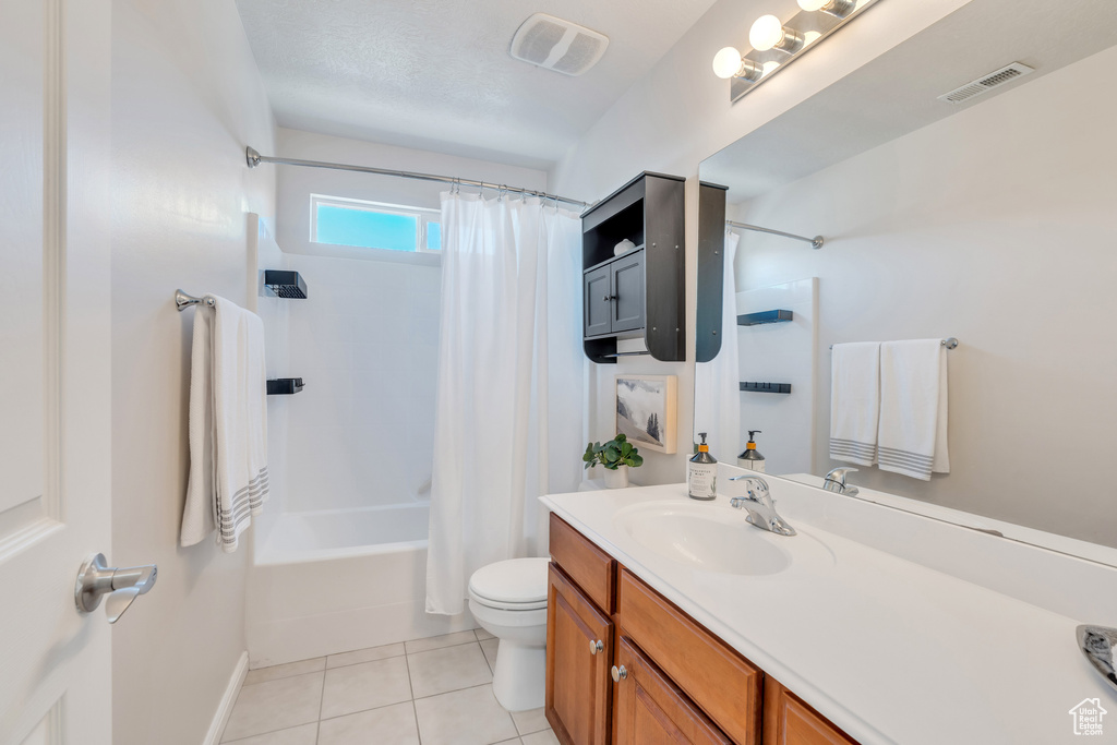 Full bathroom featuring toilet, a textured ceiling, shower / bathtub combination with curtain, large vanity, and tile floors