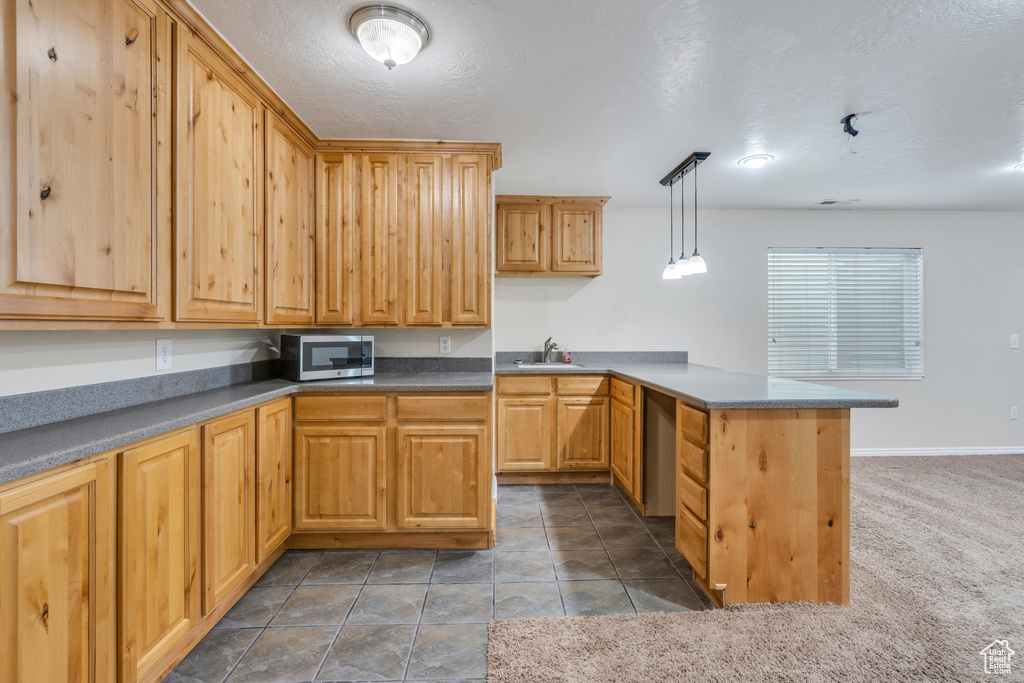 Kitchen with dishwasher, decorative light fixtures, sink, kitchen peninsula, and carpet