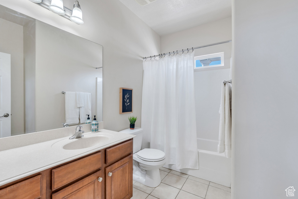 Full bathroom with toilet, vanity, shower / tub combo with curtain, and tile floors