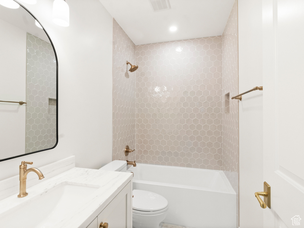 Full bathroom featuring vanity with extensive cabinet space, toilet, and tiled shower / bath