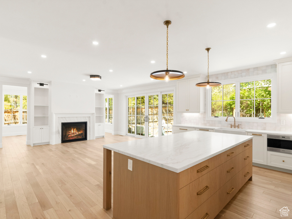 Kitchen featuring a wealth of natural light, light hardwood / wood-style floors, hanging light fixtures, and white cabinets