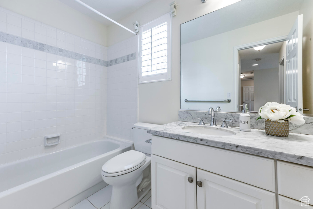 Full bathroom featuring tile floors, tiled shower / bath, vanity, and toilet