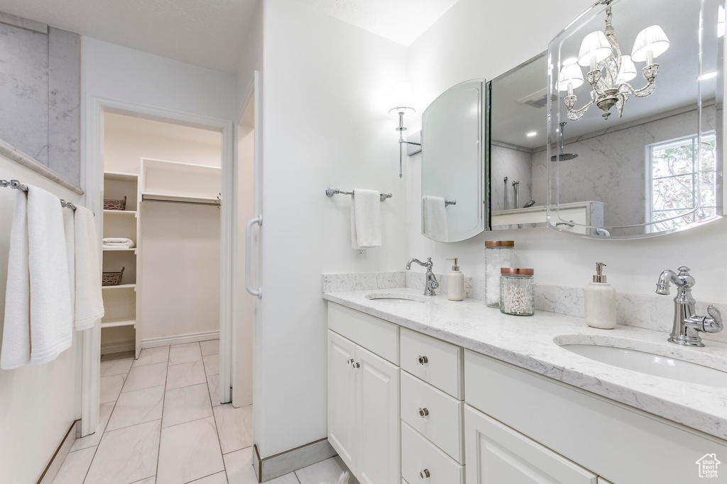 Bathroom with tile flooring, double sink vanity, and a notable chandelier