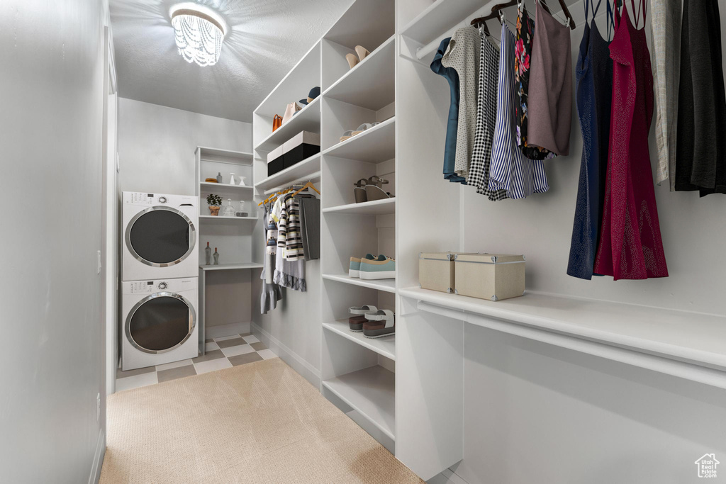 Walk in closet with light carpet and stacked washer and dryer