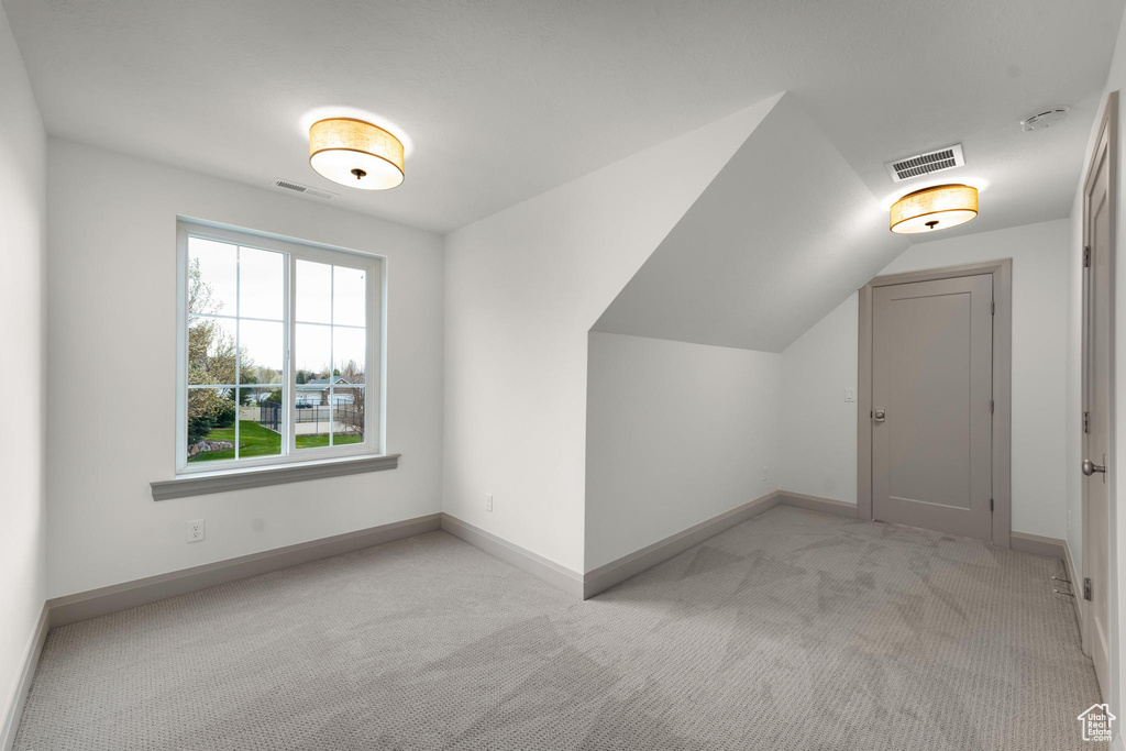 Bonus room featuring vaulted ceiling and light colored carpet