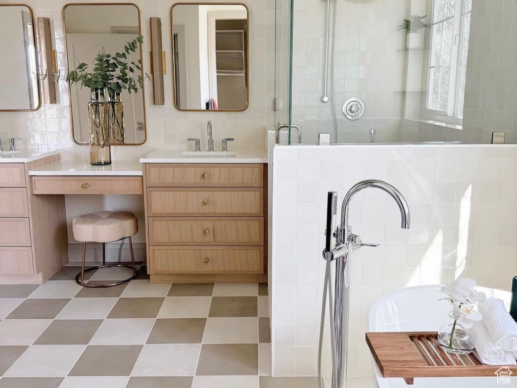 Bathroom with tile flooring, tile walls, tasteful backsplash, and vanity with extensive cabinet space