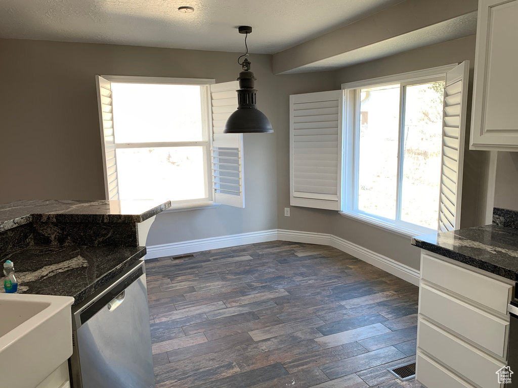 Kitchen with pendant lighting, dark wood-type flooring, dark stone countertops, dishwasher, and white cabinetry