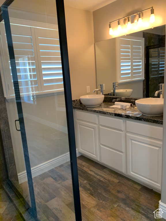 Bathroom featuring dual vanity, walk in shower, and hardwood / wood-style floors