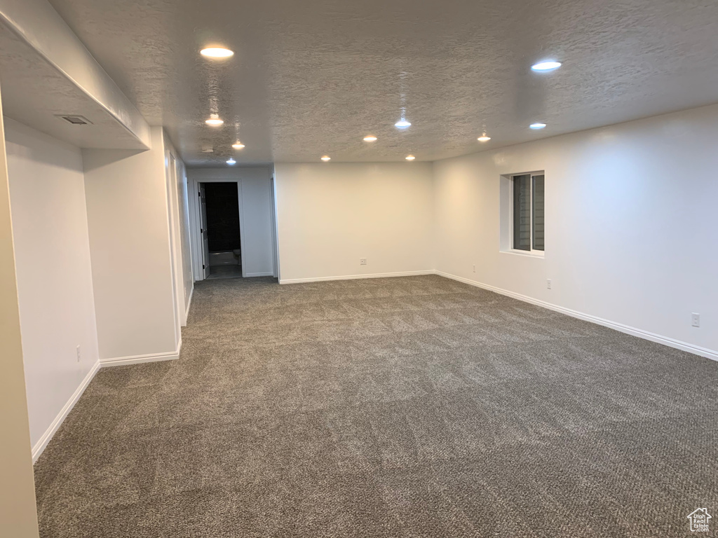 Interior space with a textured ceiling and dark colored carpet