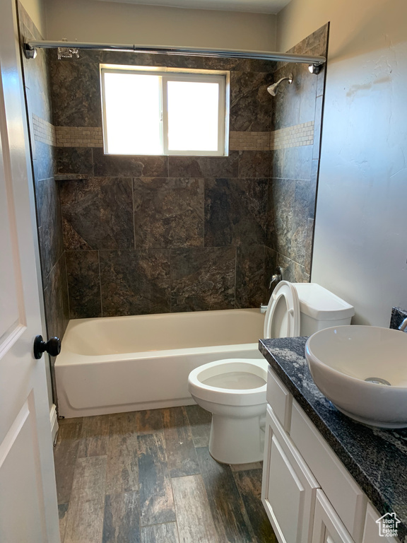 Full bathroom featuring tiled shower / bath combo, toilet, hardwood / wood-style flooring, and vanity