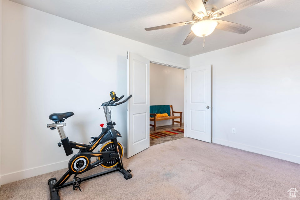 Workout room with ceiling fan and light colored carpet
