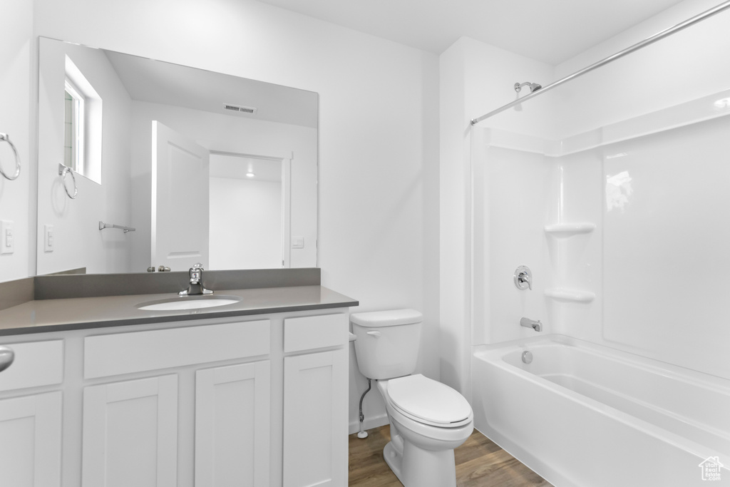 Full bathroom with toilet, wood-type flooring, vanity, and tub / shower combination