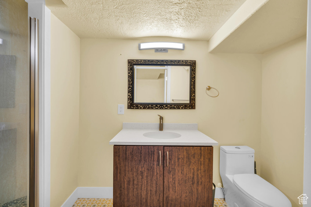 Bathroom featuring tile flooring, toilet, vanity, and a textured ceiling
