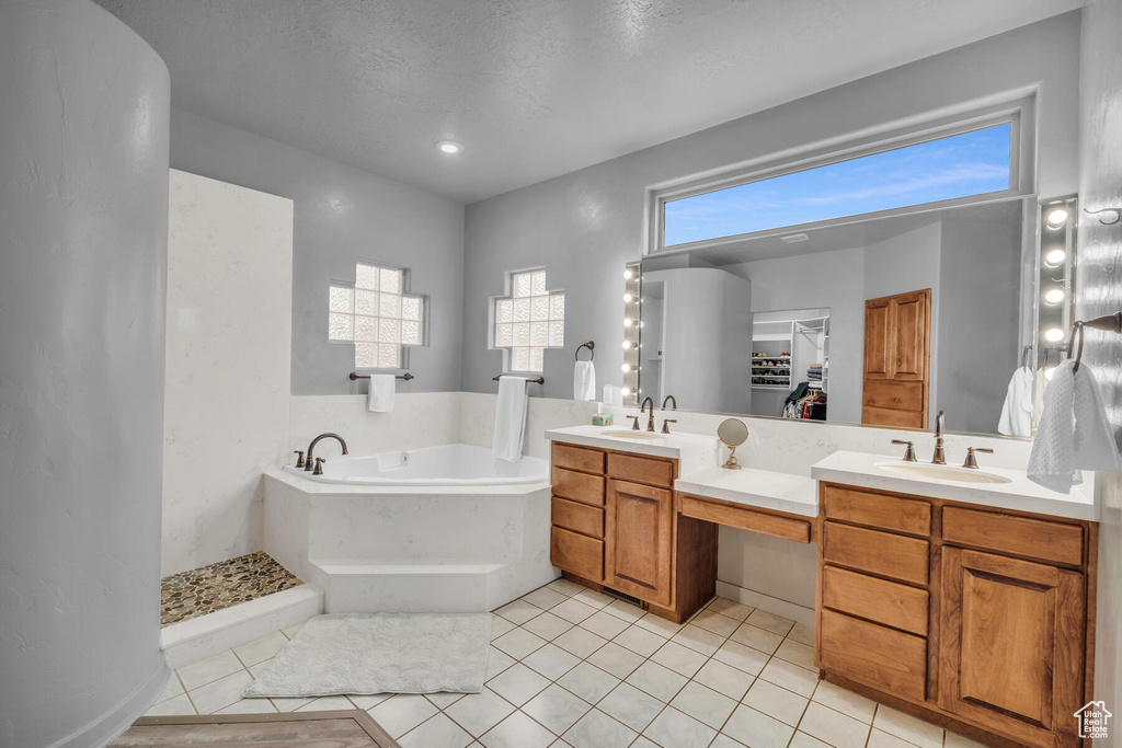 Bathroom with dual sinks, a textured ceiling, tile flooring, and vanity with extensive cabinet space